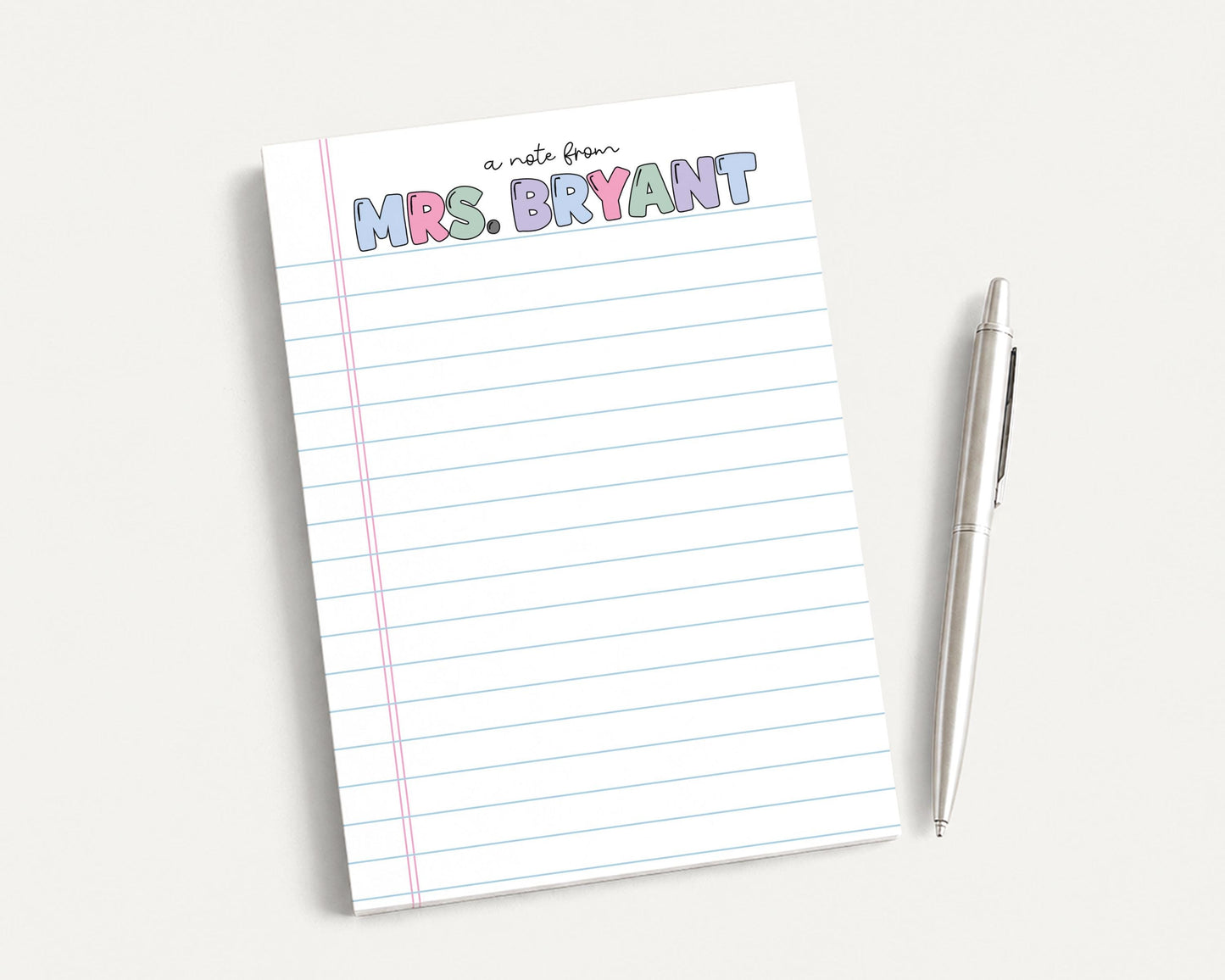 A lined notepad with the name "Mrs. Bryant" written on it, along with a pen, is placed on a white surface.