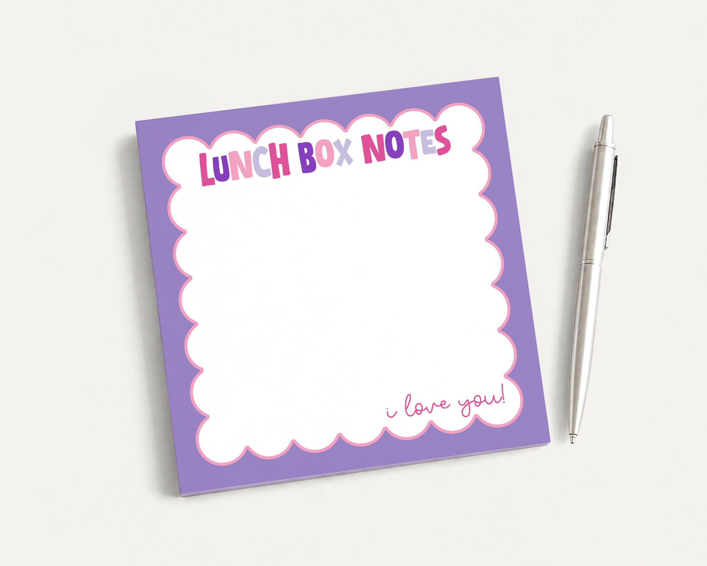 A purple sticky note pad with a blank space for writing and a pen next to it.