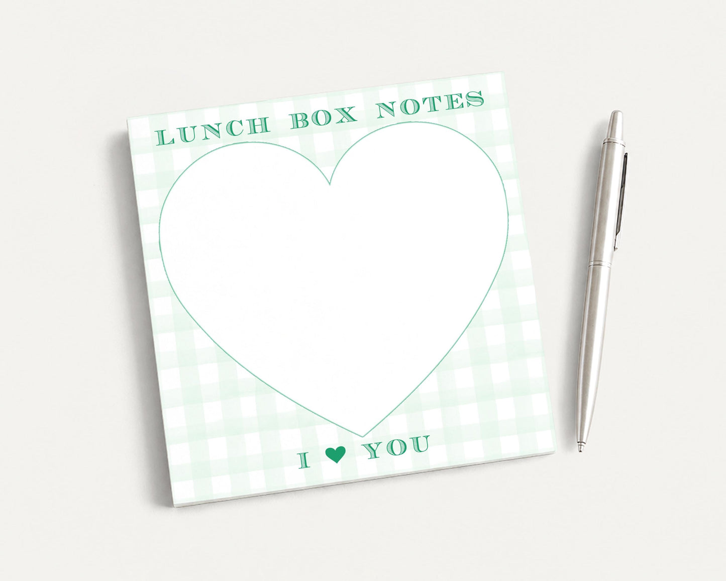a green and white checkered lunch box with a heart-shaped blank space for writing a message, accompanied by a pen.