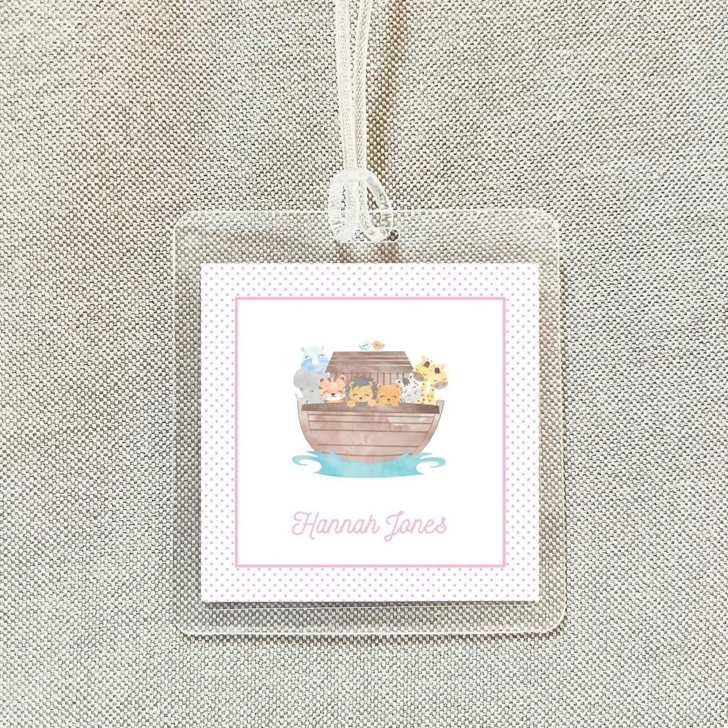 A clear plastic name tag with a pink border and a cartoon illustration of a boat filled with animals.