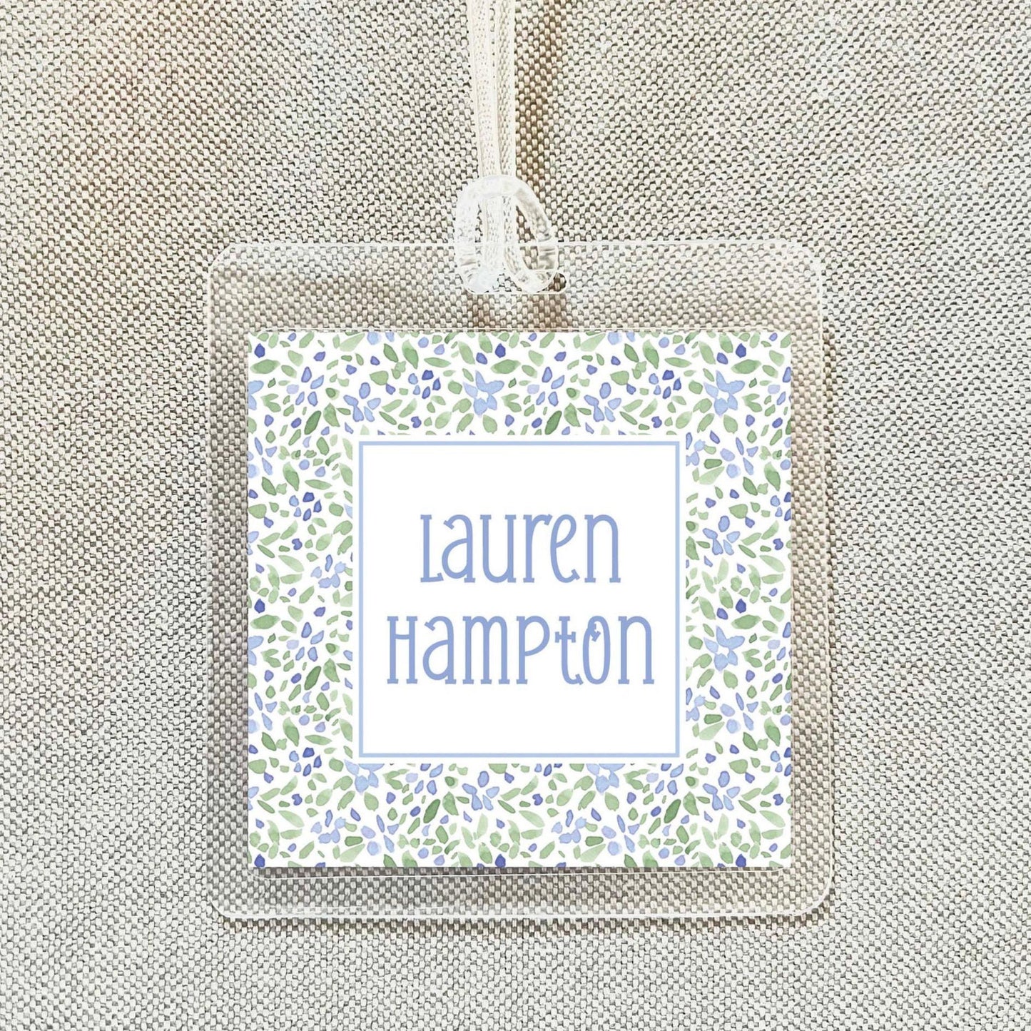 A clear name tag with a floral pattern and the name "Lauren Hampton" printed on it.
