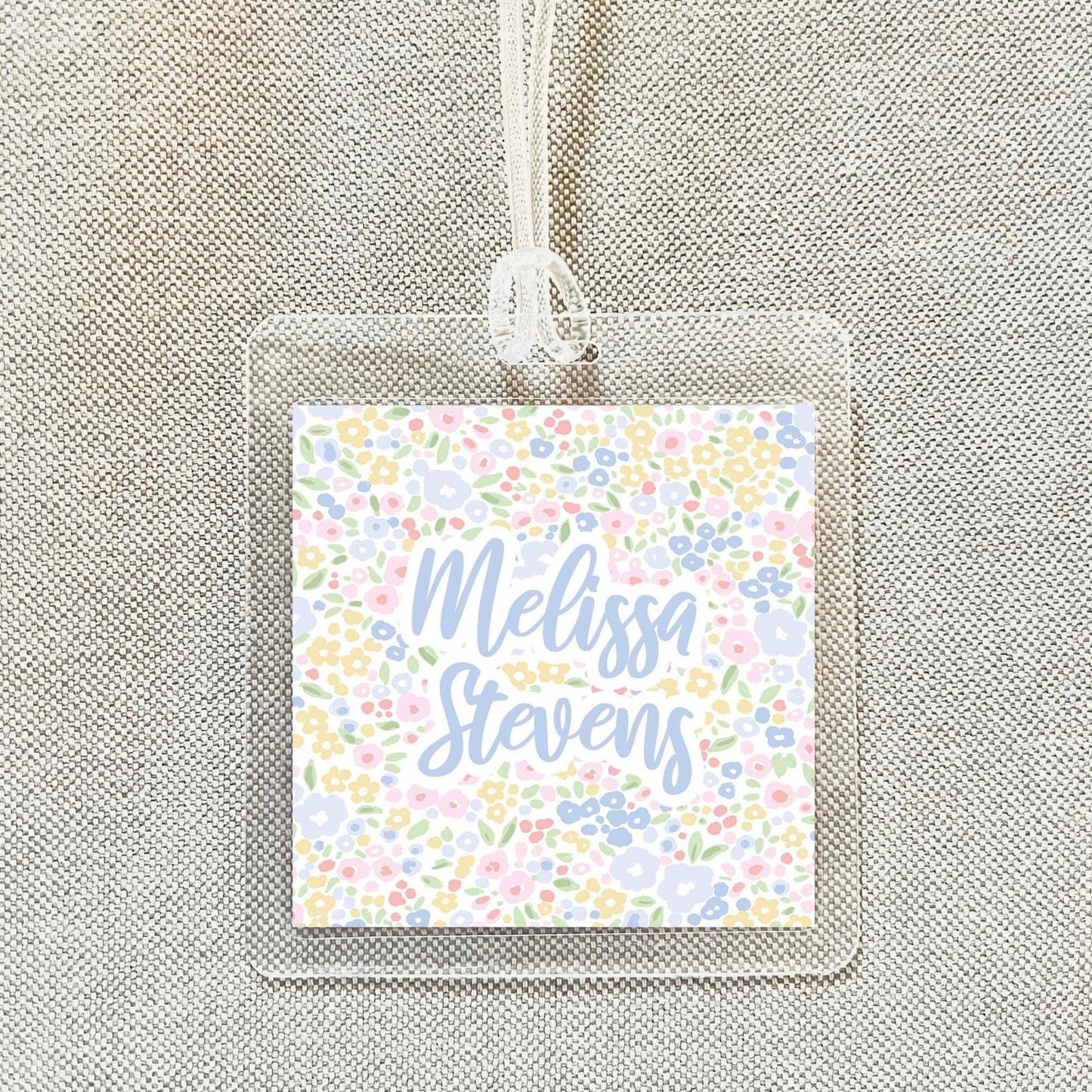 A clear plastic name tag with a floral design and the name "Melissa Stevens" printed on it.