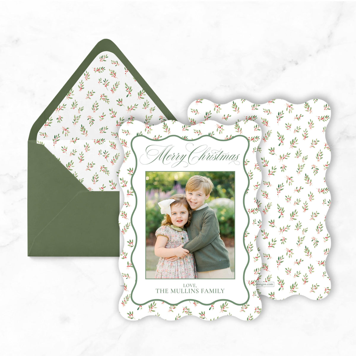 A Christmas card with a photo of a young girl and boy, along with a green envelope with a floral pattern.