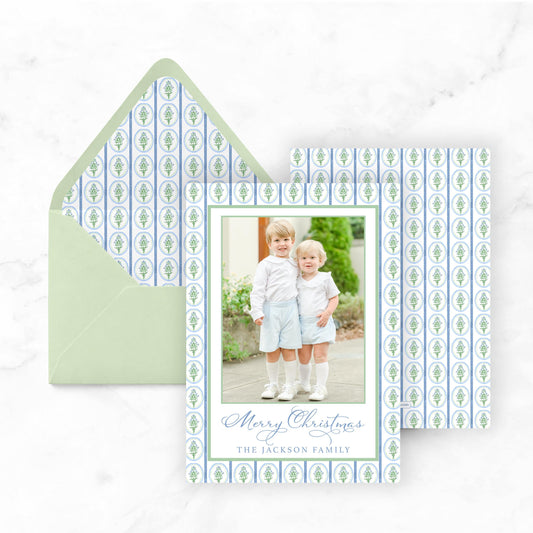 A Christmas card featuring two young boys in a family photo, with a green envelope and a patterned background.