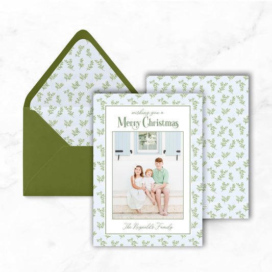 A green envelope with a white pattern and a greeting card featuring a family photo.