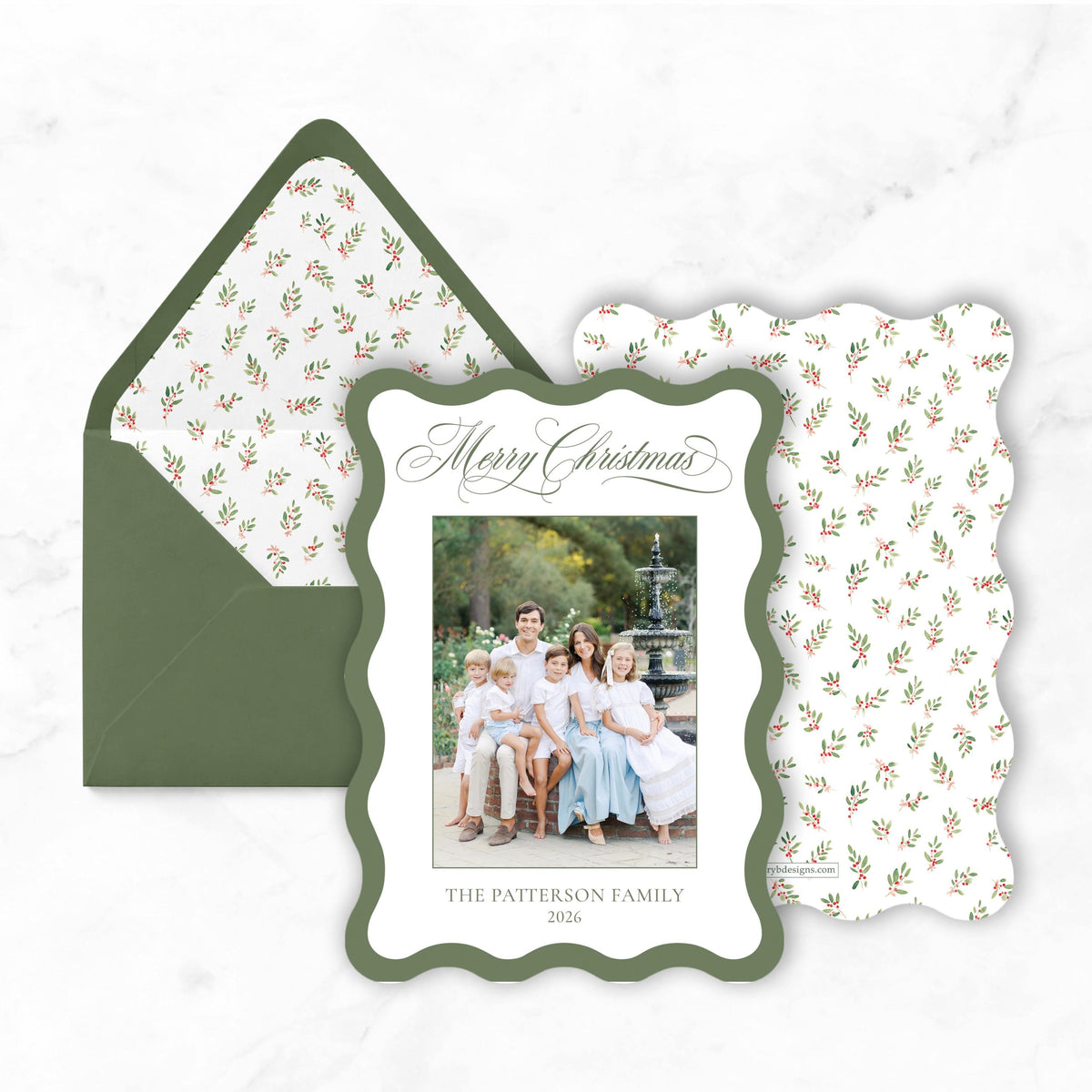 A green envelope with a white floral pattern and a white frame containing a family photo.