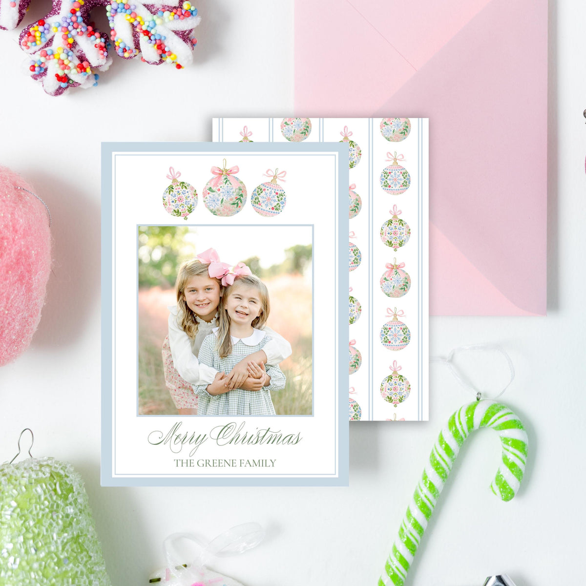 a variety of Christmas-themed items, including a snowflake ornament, a pink envelope, a photo frame, a candy cane, and other ornaments, all arranged on a white background.