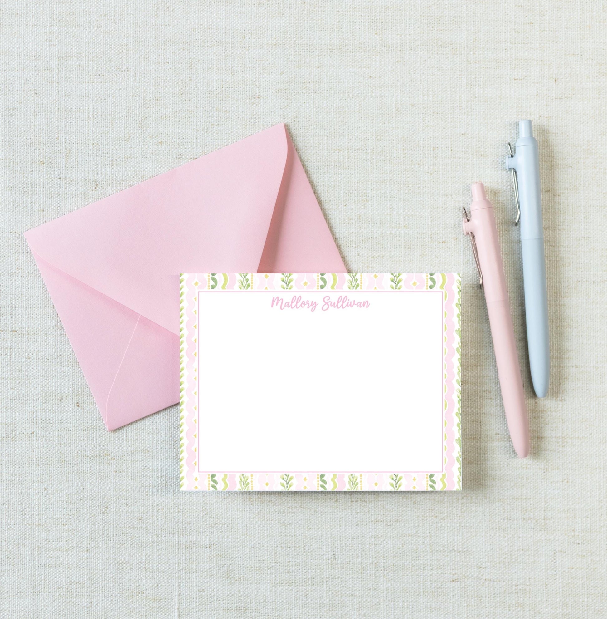 a pink envelope, a blank note card with a floral border, and two pens on a light-colored surface. __etsy:8233148293