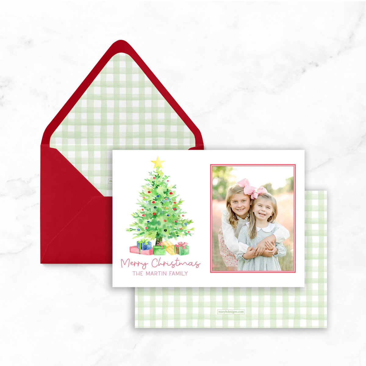 A Christmas card with a red envelope and a photo of two young girls posing together.