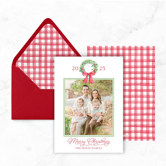 A Christmas card with a family photo and a red envelope with a red and white checkered pattern.