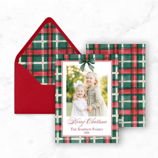 A Christmas card with a red envelope and a photo of two young girls smiling.