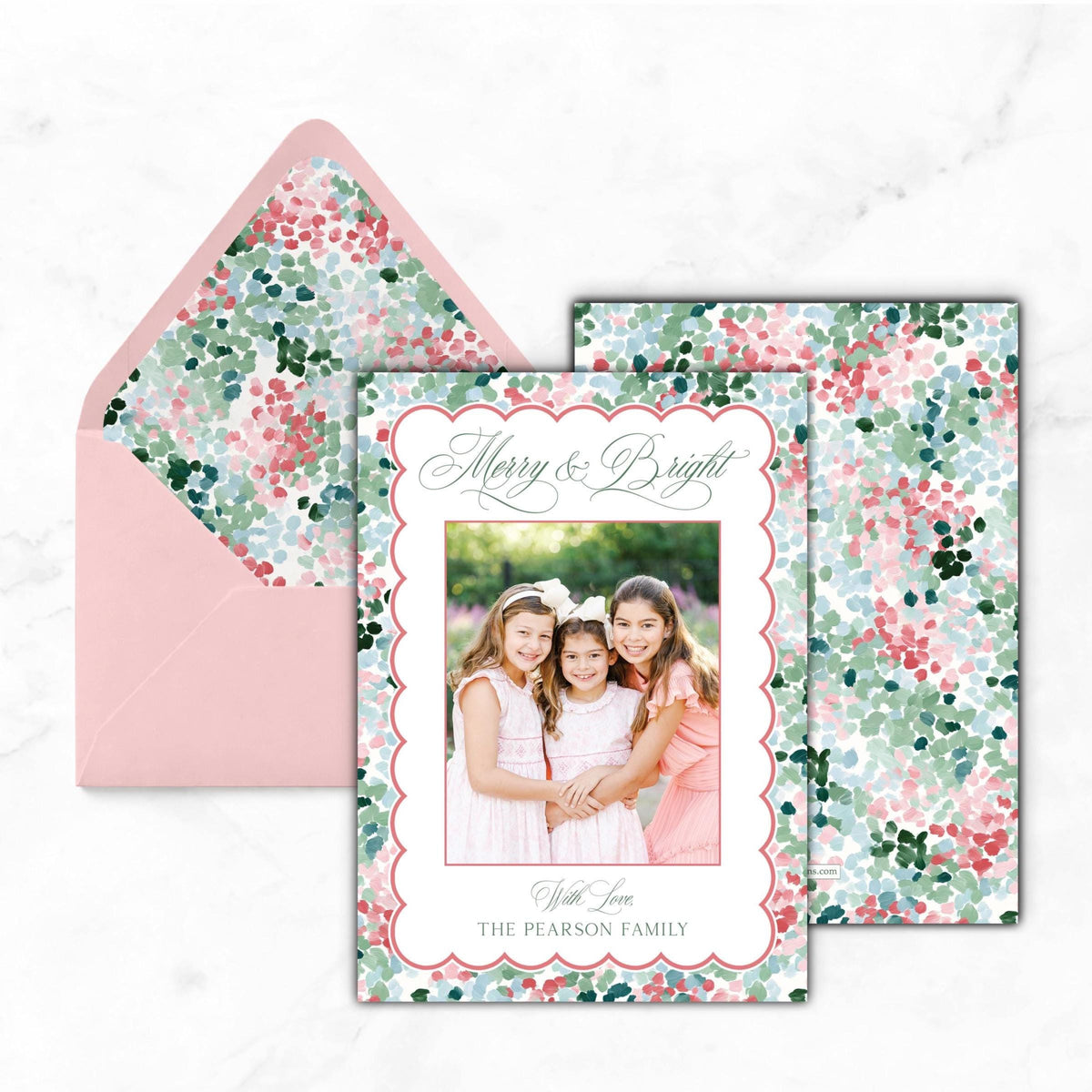 A pink floral-patterned envelope with a photo of three young girls inside, and a card with a floral design and text on it.