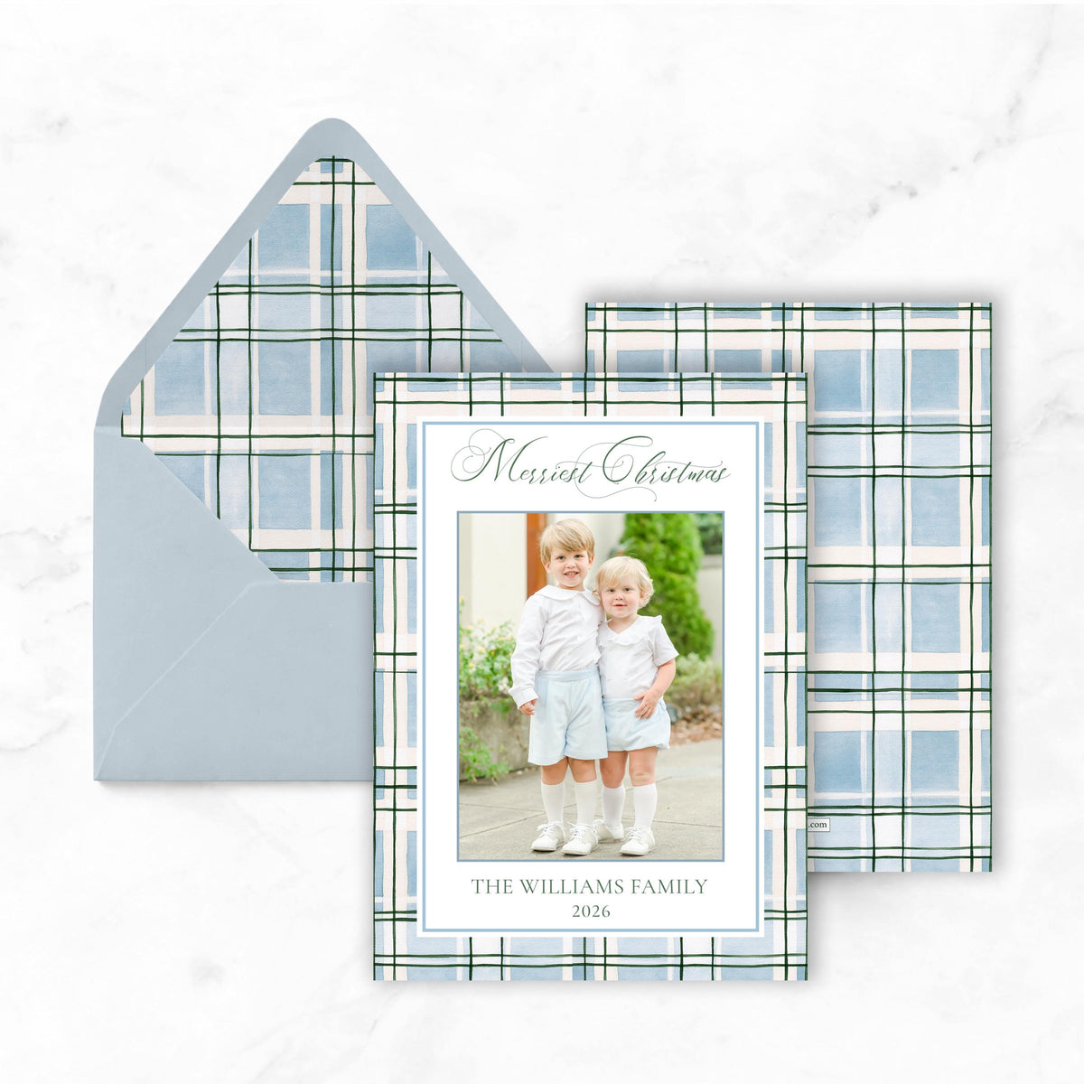 A greeting card with a photo of two young children, likely siblings, and the text "Merry Christmas" and "THE WILLIAMS FAMILY 2026" printed on it.