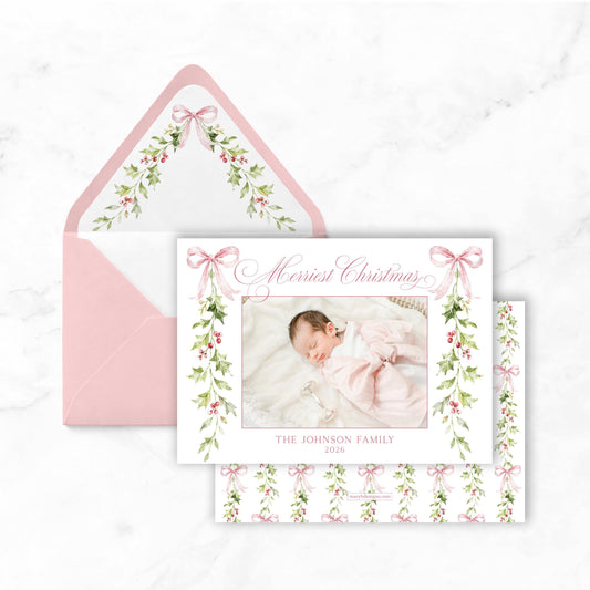 A pink envelope with a photo of a baby inside, and a white card with a floral design and text on it.