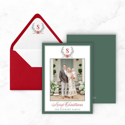 A Christmas card featuring a family photo of a man, woman, and child, along with a red envelope and a green card.