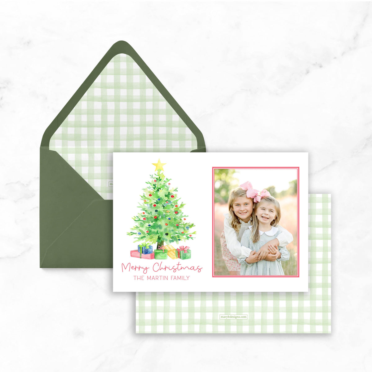 A Christmas card with a green envelope and a photo of two young girls posing together.