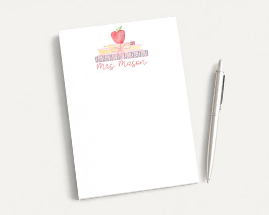 A white notepad with a watercolor illustration of a stack of books and an apple on top, along with the text "Mrs. Mason".