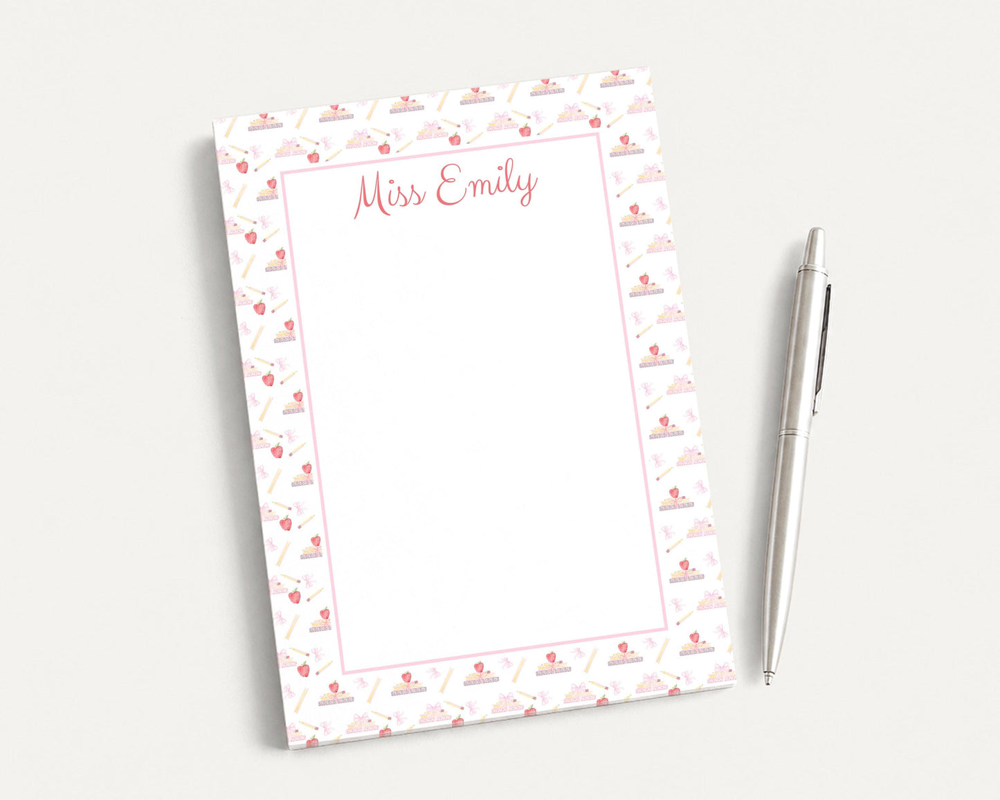 a blank nameplate with a pink and white patterned border, placed next to a pen on a white surface.