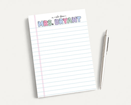 A lined notepad with the name "Mrs. Bryant" written on it, along with a pen, is placed on a white surface.