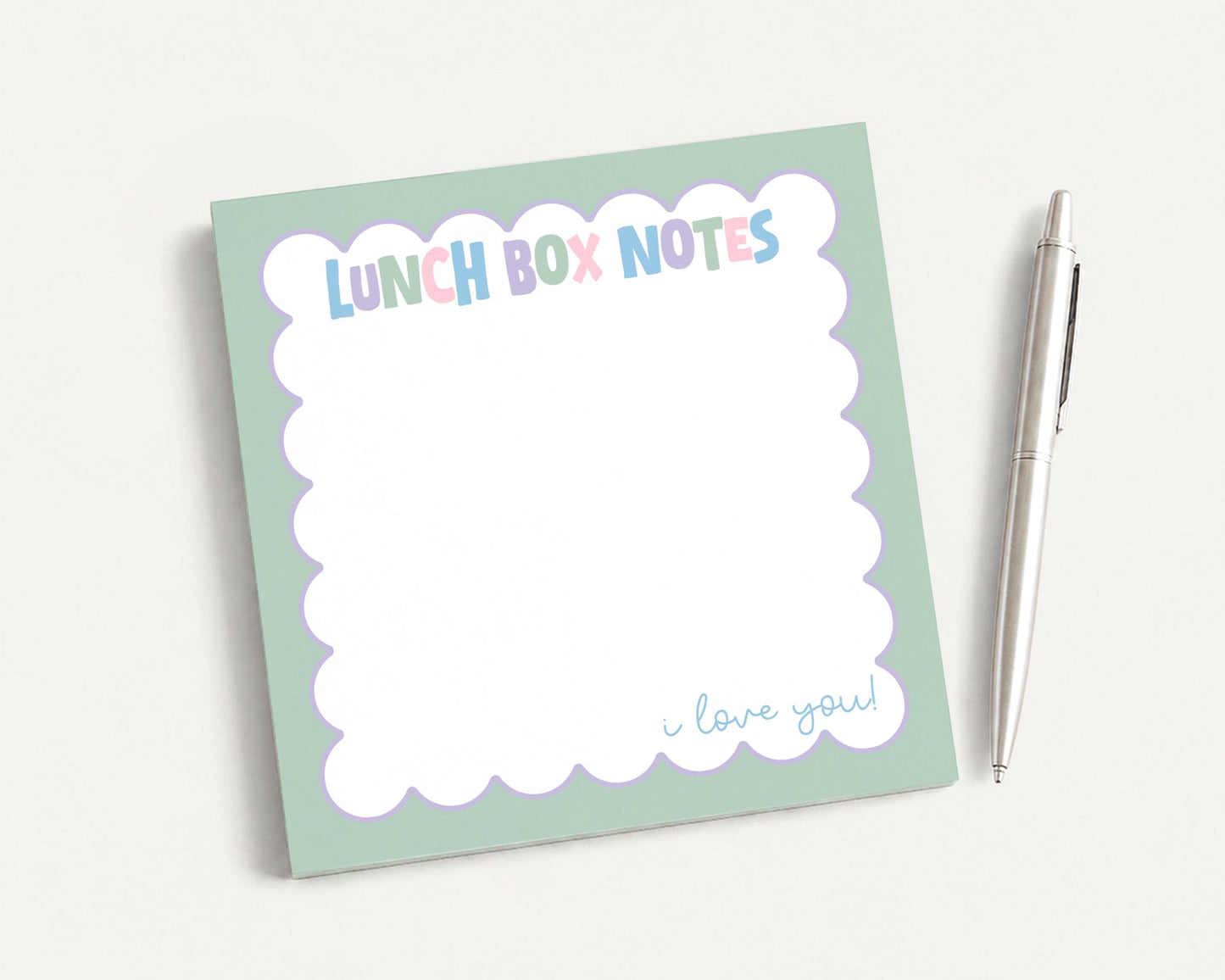 A green sticky note pad with the text "LUNCH BOX NOTES" and a pen next to it.