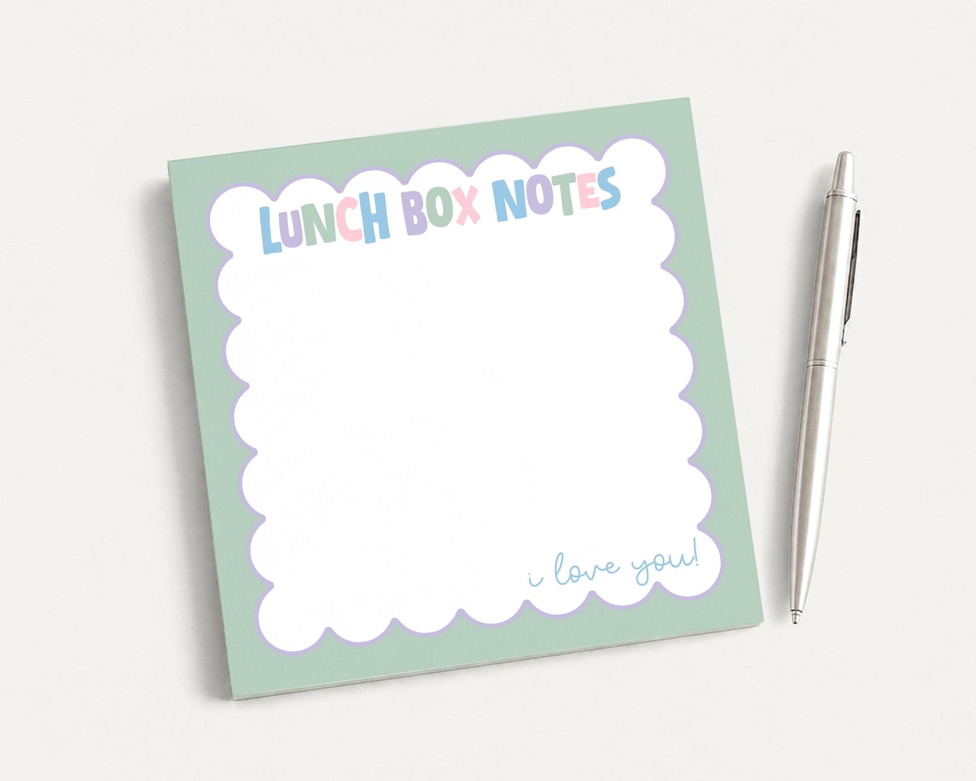 A green sticky note pad with the text "LUNCH BOX NOTES" and a pen next to it.