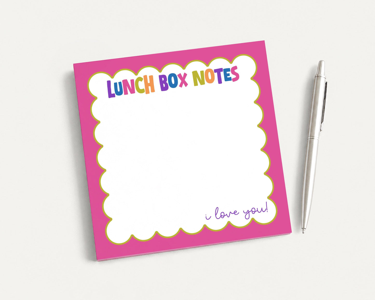 A pink sticky note pad with a blank space for writing and a pen next to it.