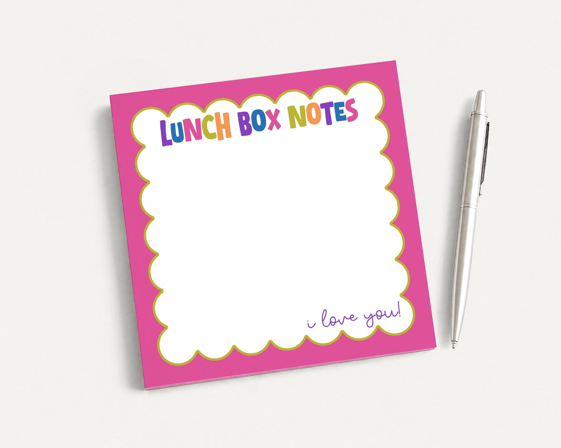 A pink sticky note pad with a blank space for writing and a pen next to it.