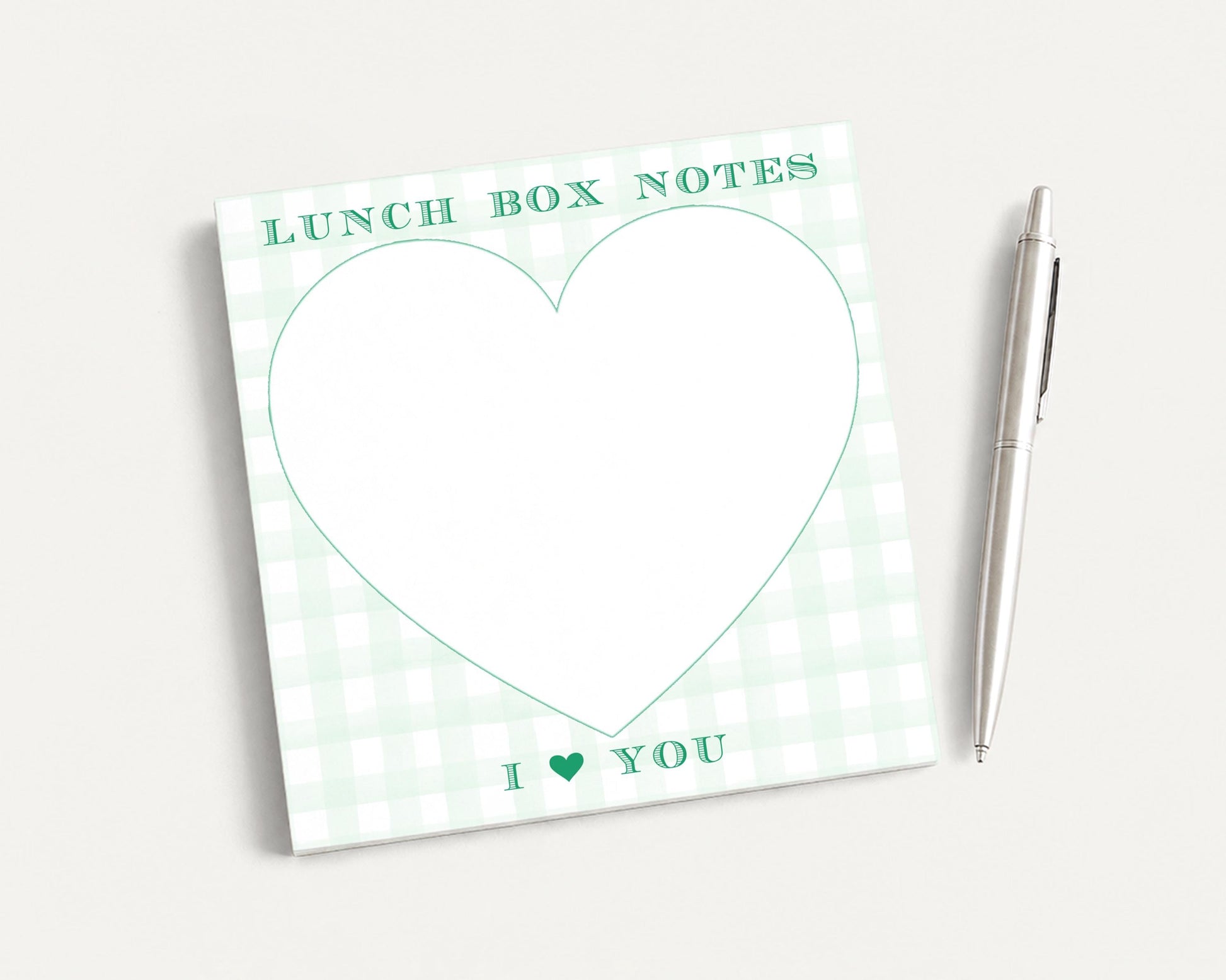 a green and white checkered lunch box with a heart-shaped blank space for writing a message, accompanied by a pen.