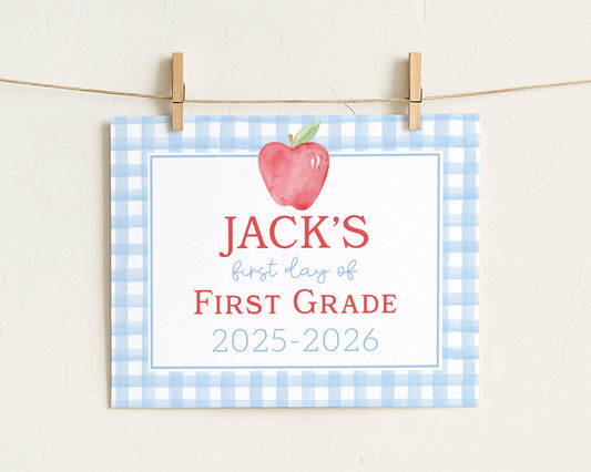A blue and white checkered sign with a red apple and the text "JACK'S first day of FIRST GRADE" hanging on a clothesline.