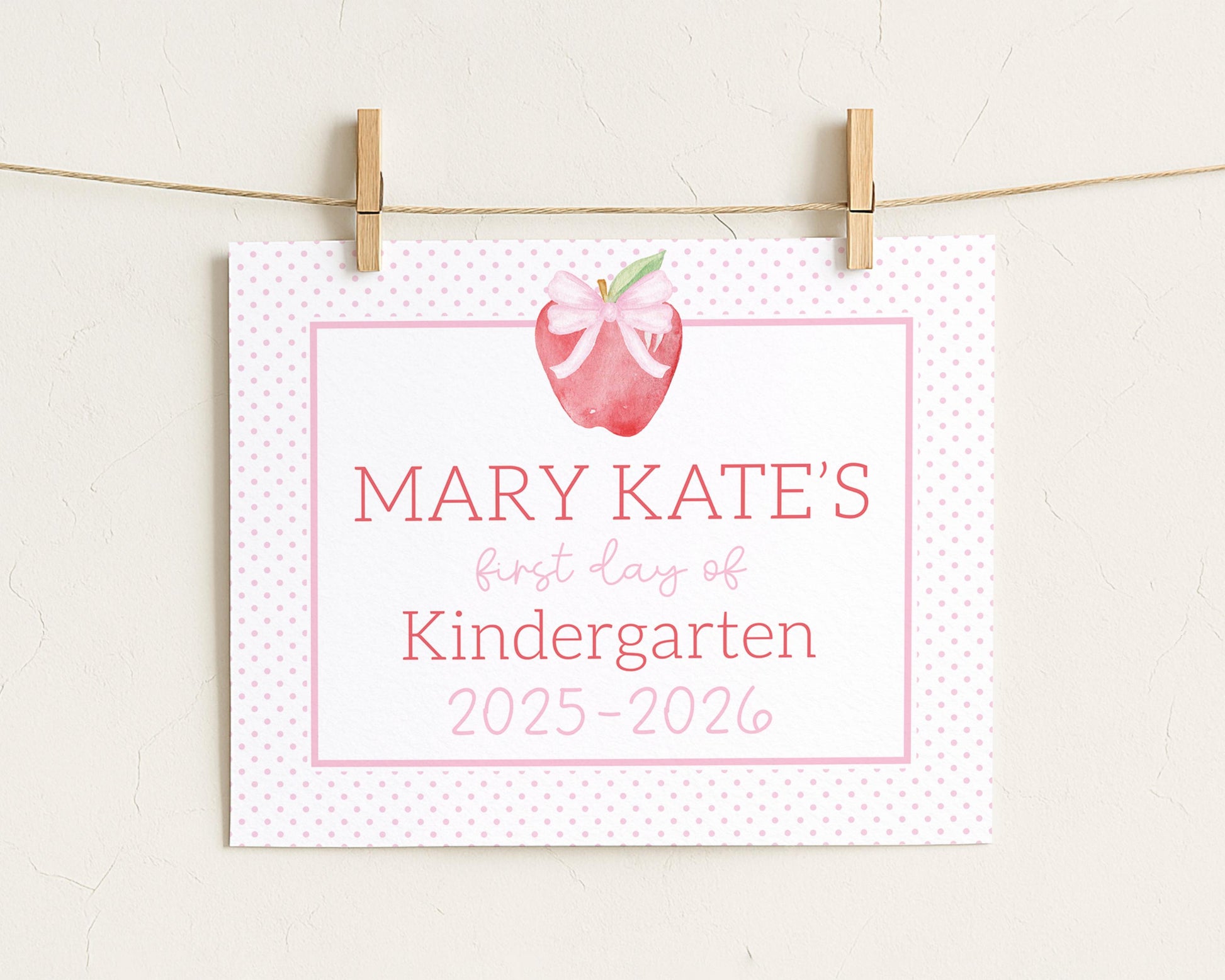 A white sign with pink polka dots and an apple graphic, hanging on a string.