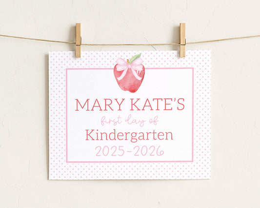 A white sign with pink polka dots and an apple graphic, hanging on a string.