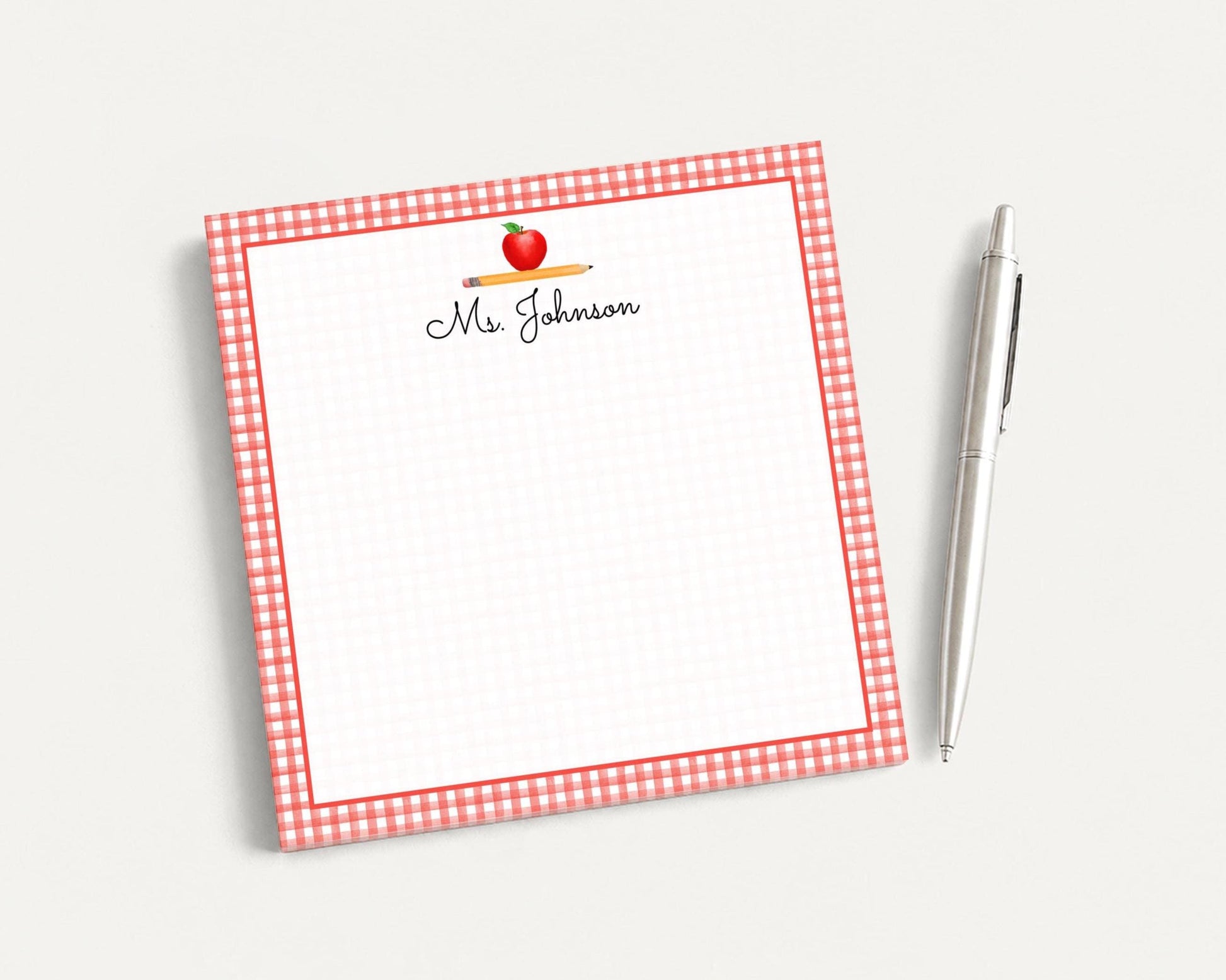 A red and white checkered notepad with a pen next to it, placed on a plain white surface.