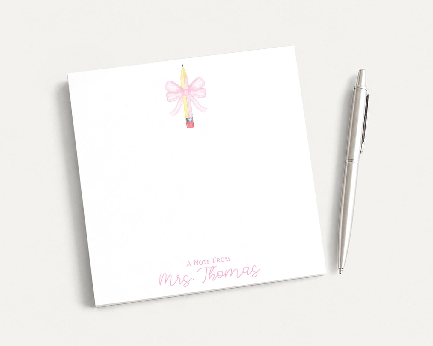 A white notepad with a pink bow and a pen on a white background.