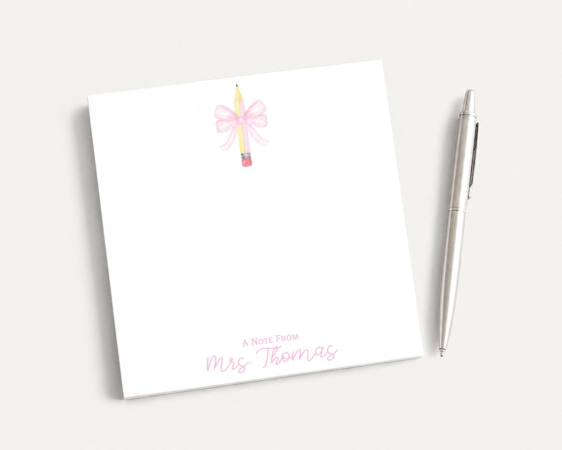A white notepad with a pink bow and a pen on a white background.