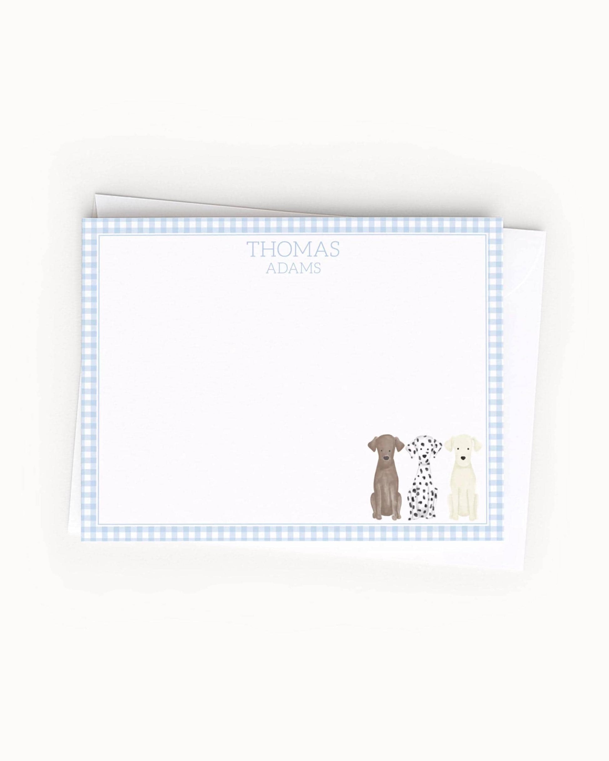 A blank card with a blue and white checkered border, featuring illustrations of three dogs of different breeds.