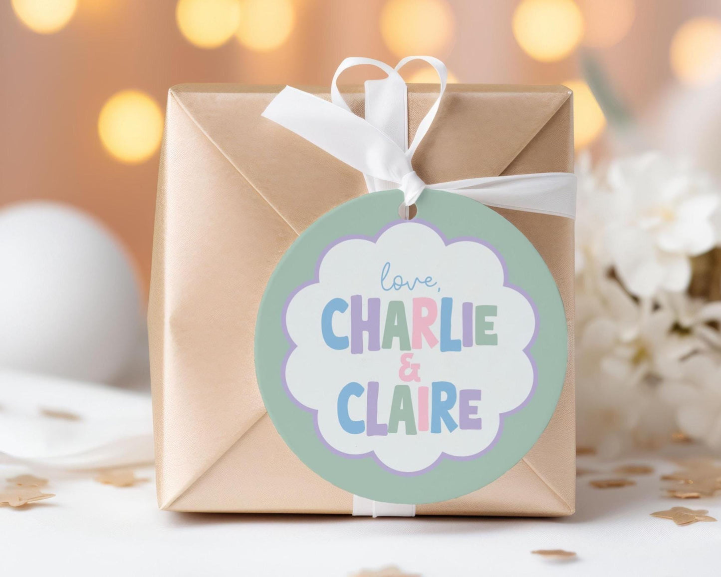A gift box with a round tag that says "love Charlie & Claire" is placed on a table with scattered gold confetti.