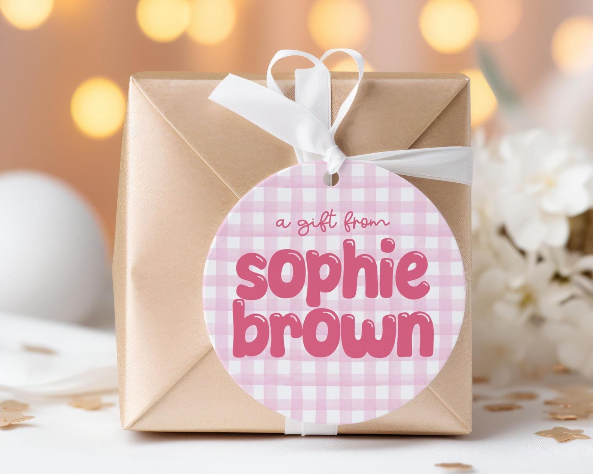 A gift wrapped in brown paper with a pink and white checkered tag that says "a gift from Sophie Brown".