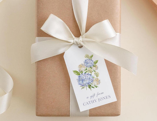 A gift wrapped in brown paper with a white ribbon and a white tag featuring a floral design.
