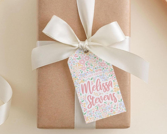 A brown gift box with a white ribbon and a tag that reads "Melissa Stevens" printed on it.