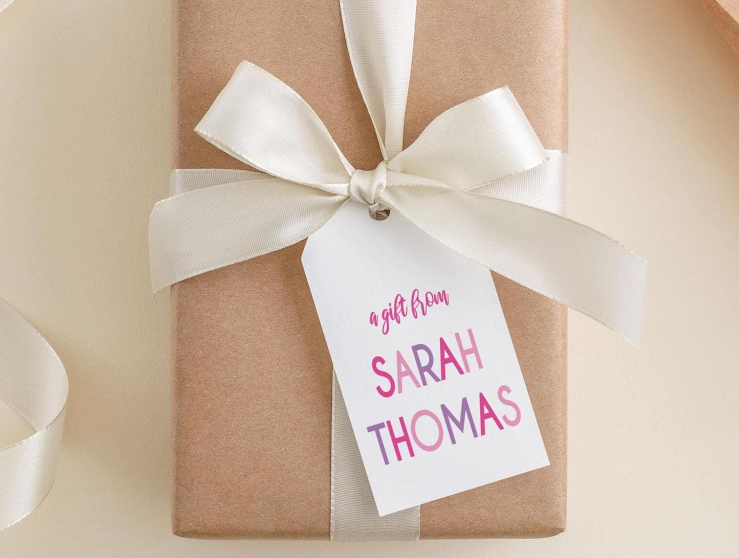 A gift wrapped in brown paper with a white ribbon and a tag that reads "a gift from Sarah Thomas".