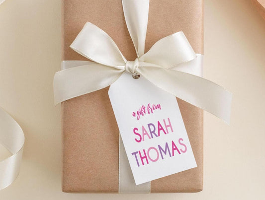 A gift wrapped in brown paper with a white ribbon and a tag that reads "a gift from Sarah Thomas".