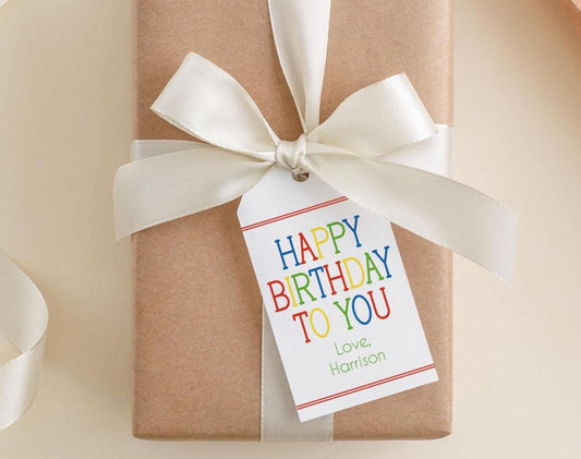 A brown gift box with a white ribbon and a white tag that reads "Happy Birthday to You" and "Love, Harrison".