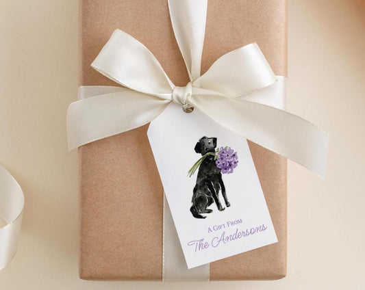 A gift wrapped in brown paper with a white ribbon and a tag featuring a black dog holding purple flowers.