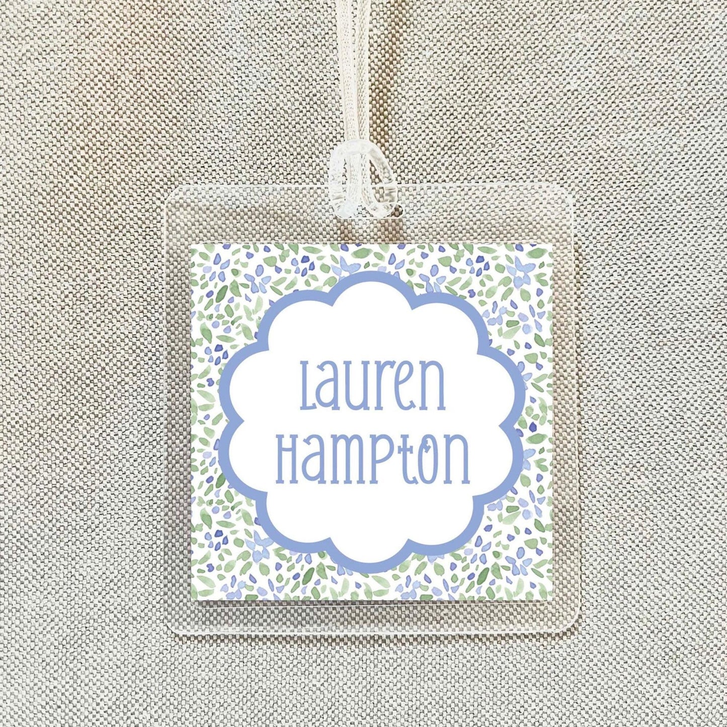 A clear plastic name tag with a floral design and the name "Lauren Hampton" printed on it.