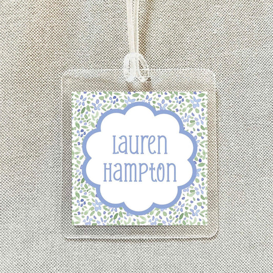 A clear plastic name tag with a floral design and the name "Lauren Hampton" printed on it.