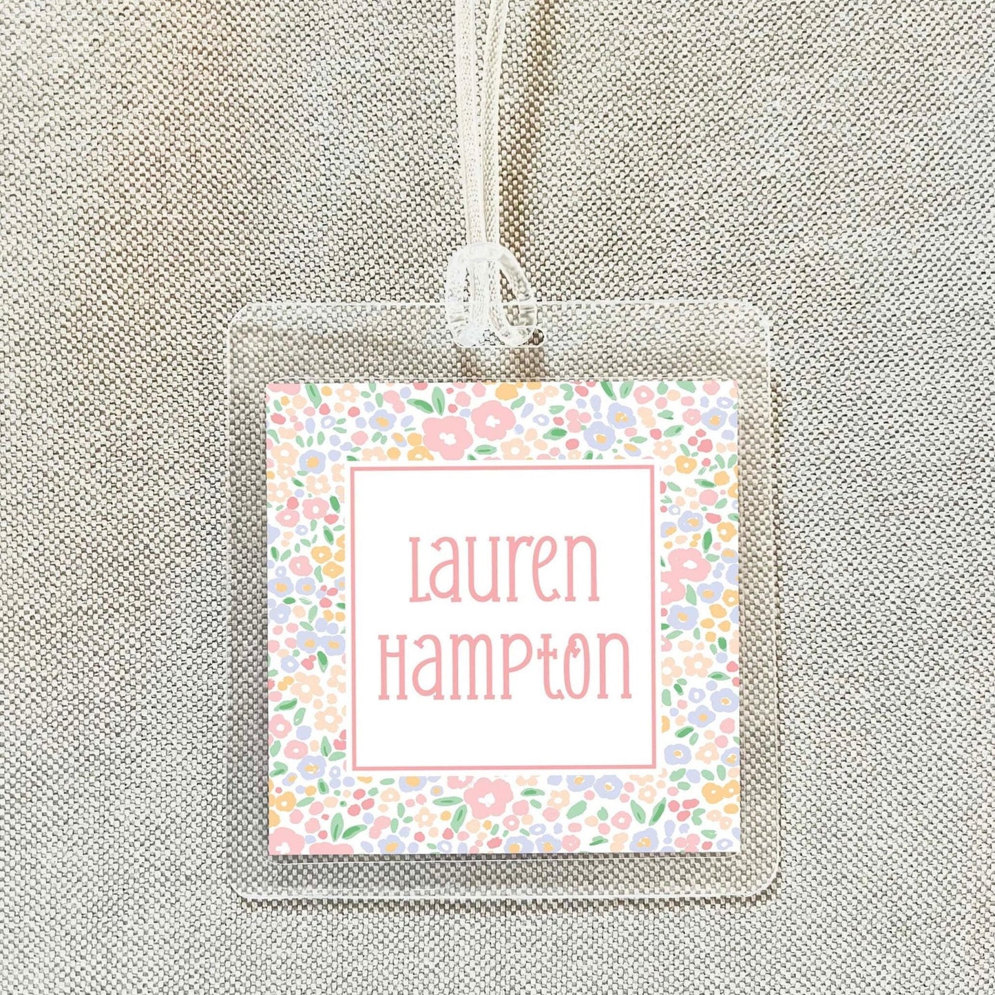 A clear plastic name tag with a floral design and the name "Lauren Hampton" printed on it.