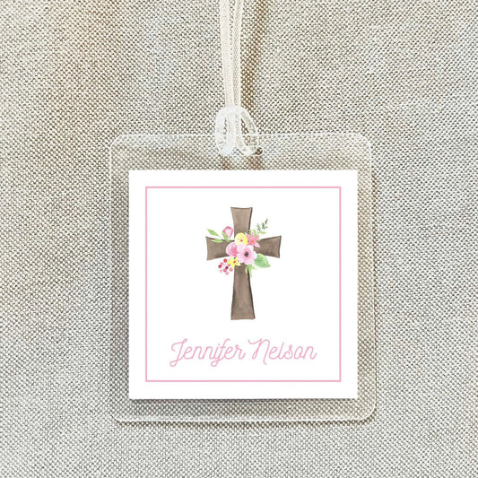 A clear name tag with a pink border and a cross design, featuring the name "Jennifer Nelson" written in cursive.