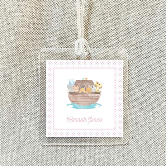 A clear plastic name tag with a pink border and a cartoon illustration of a boat filled with animals.