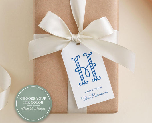 A gift box with a white ribbon and a tag that reads "A gift from The Harrisons" is placed on a beige surface.