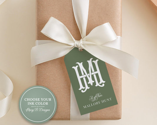 A brown gift box with a white ribbon and a green tag displaying the initials "H.M."